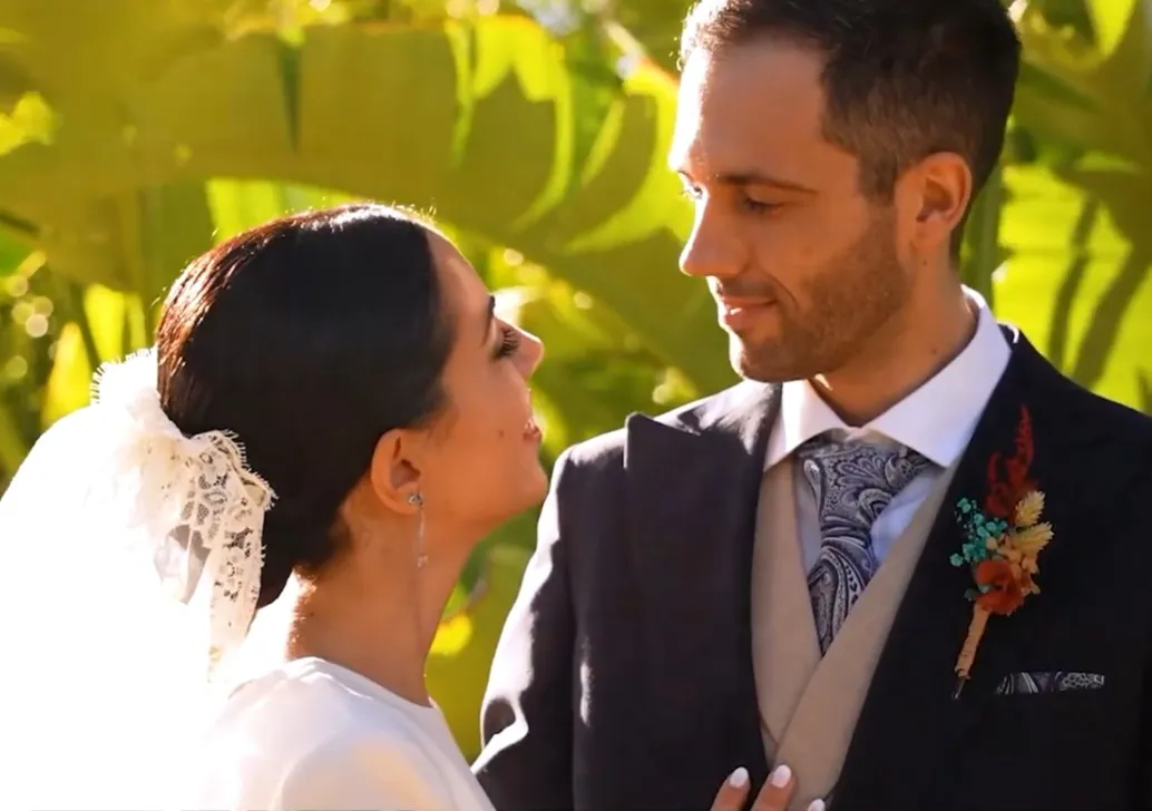 Los novios mirándose entre hojas verdes