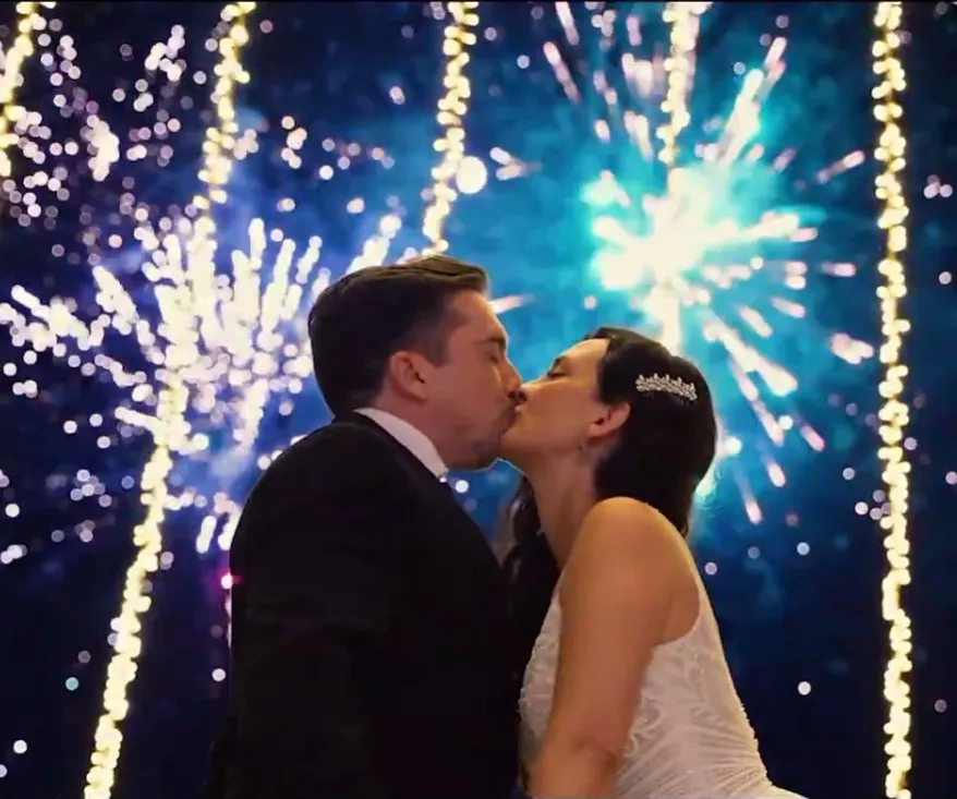 Pareja besándose bajo fuegos artificiales y guirnaldas de luces